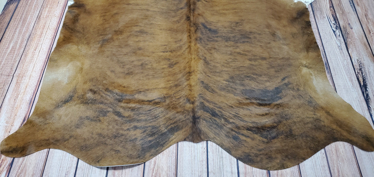 A tan brindle cowhide rug is the perfect way to add a unique touch of rustic charm to any living space.