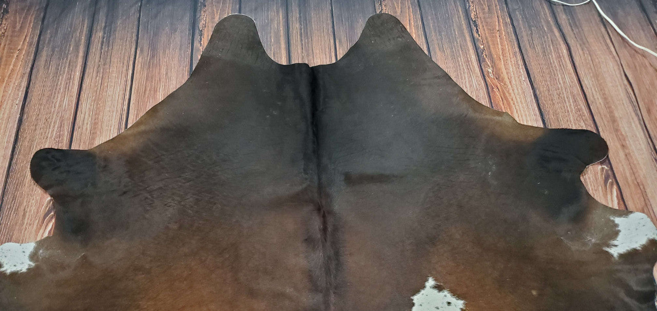 Add warmth, texture, and neutral elegance to any room with this stunning natural cowhide rug in dark brown and black colors.