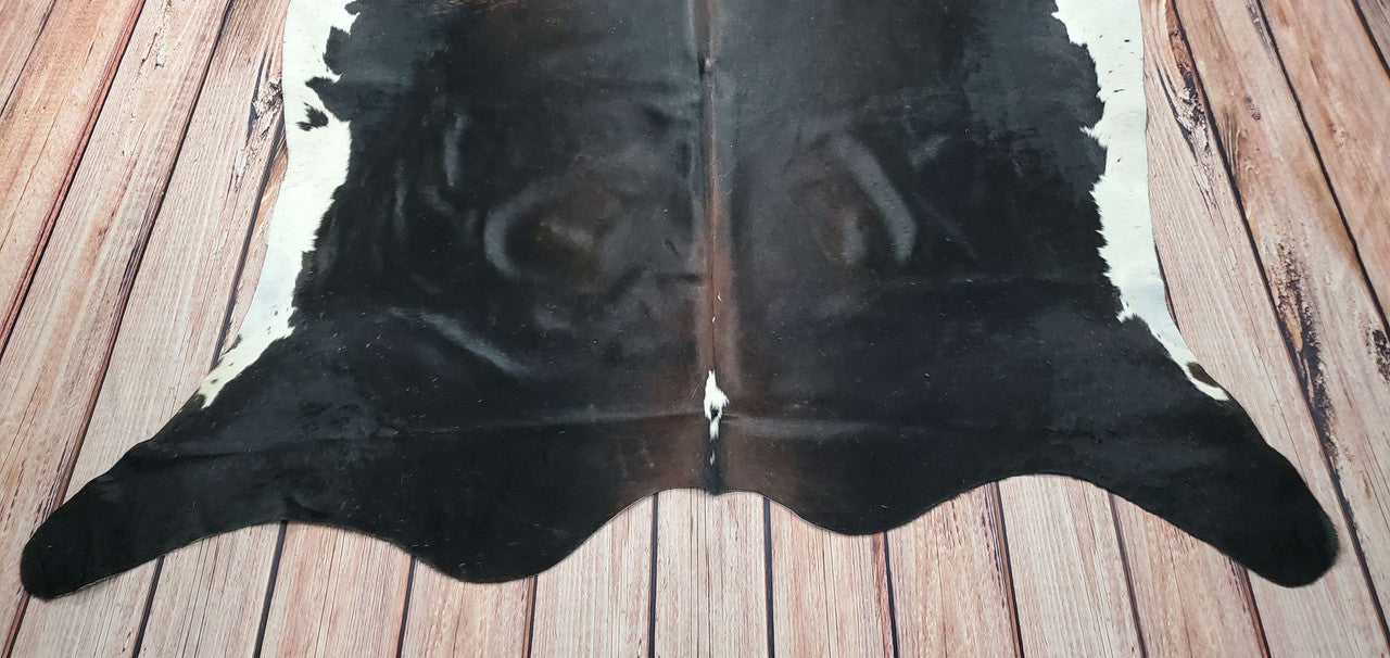 This one-of-a-kind, beautiful exotic solid black with brown spine cowhide rug is the perfect statement piece for any room. This unique cow rug will not only bring texture and warmth to a room.