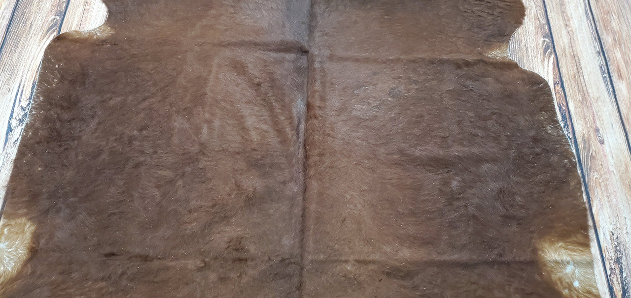 This natural brown cowhide rug is perfect for any home or office. With hints of black on the edges, it adds a stunning touch to any room.