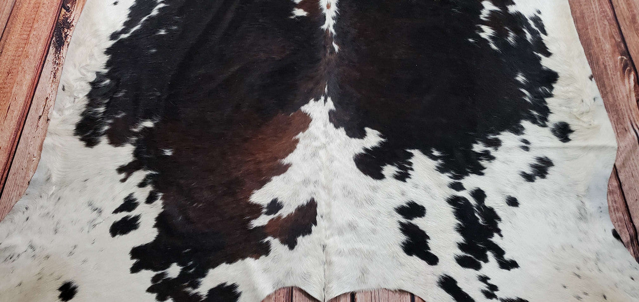 A great quality, tri-color cowhide rug with a deep, rich brown, black and white, and a somewhat detailed pattern.
