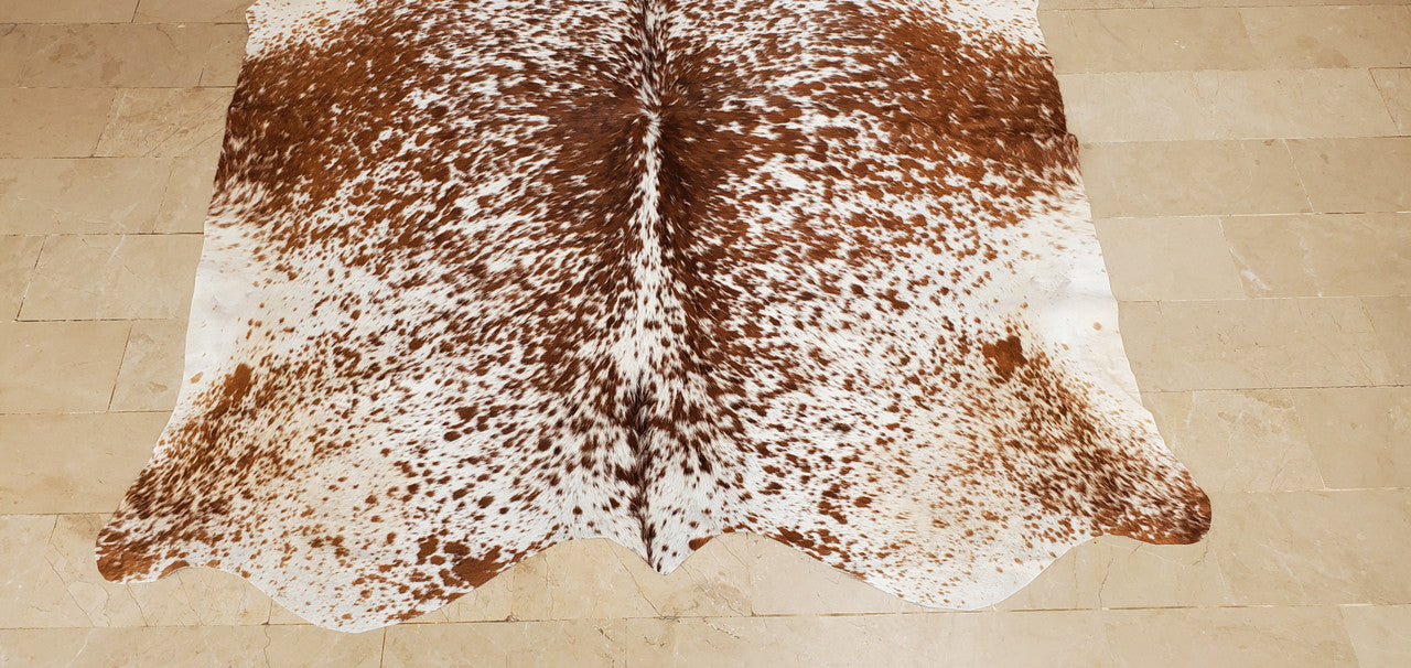 Dark brown with black blended in white on the edges, cowhide rug has an interesting touch, mix of formal and casual, when with center table and sofas