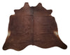 A natural cowhide rug mostly brown with hints of slight black on the edges, stunning for home or office. This luxurious, cow hide is perfect for those who want to add a touch of elegance to their space. 
