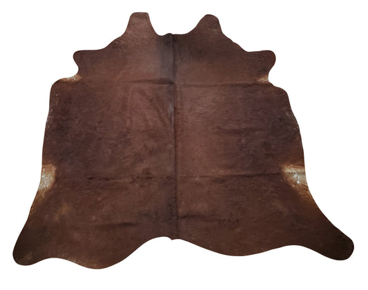 A natural cowhide rug mostly brown with hints of slight black on the edges, stunning for home or office. This luxurious, cow hide is perfect for those who want to add a touch of elegance to their space. 
