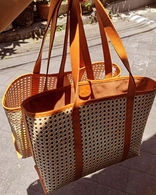 Boho rattan leather bag for beach and travel with wide base, leather handles, and breathable woven body. Great for warm-weather looks.