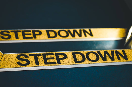 a close up of a pair of scissors near a step down sign