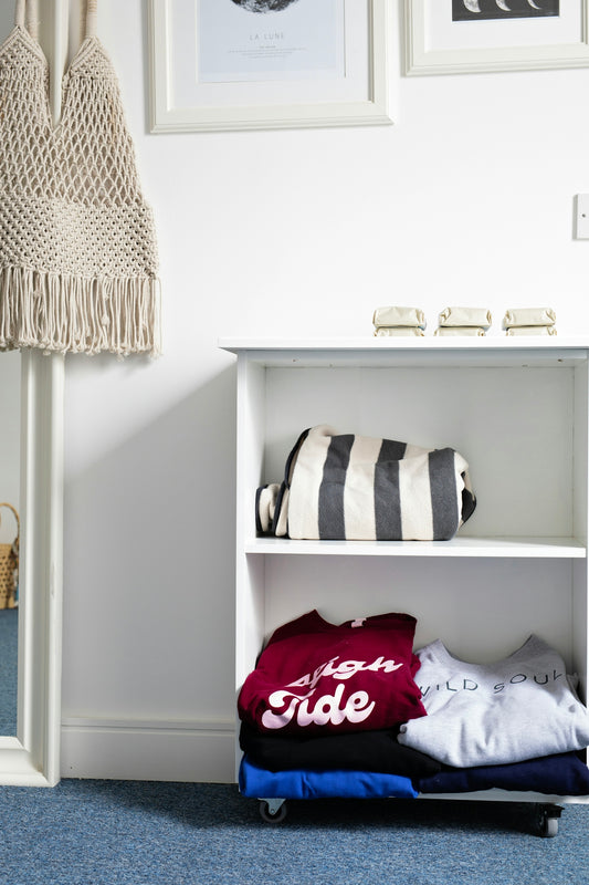 Folded clothes and striped bag on shelf.