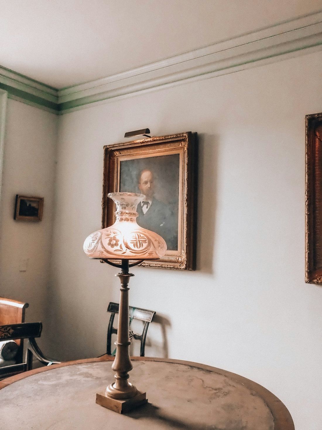 Vintage table lamp on a round table with a portrait.