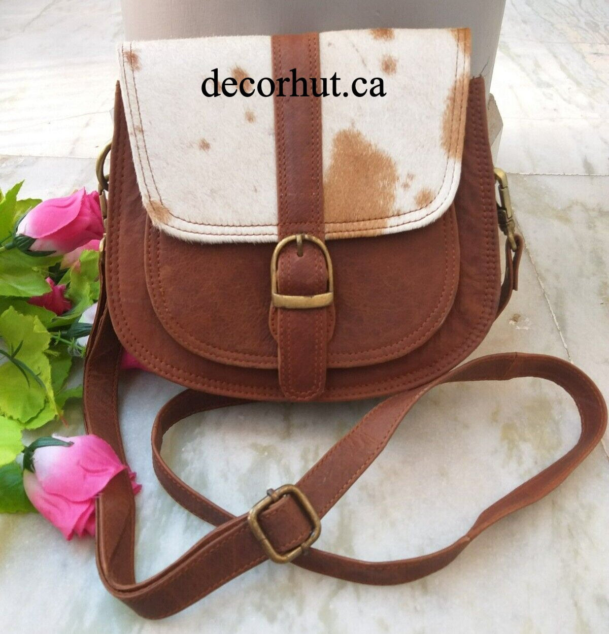 Discover a timeless look with this authentic cowhide handbag. This western-style purse features hair on leather, an adjustable strap, inside and outside pockets, and snap closure.