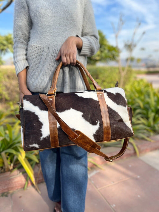 Handcrafted cowhide duffle bag with unique black, brown, and white pattern.