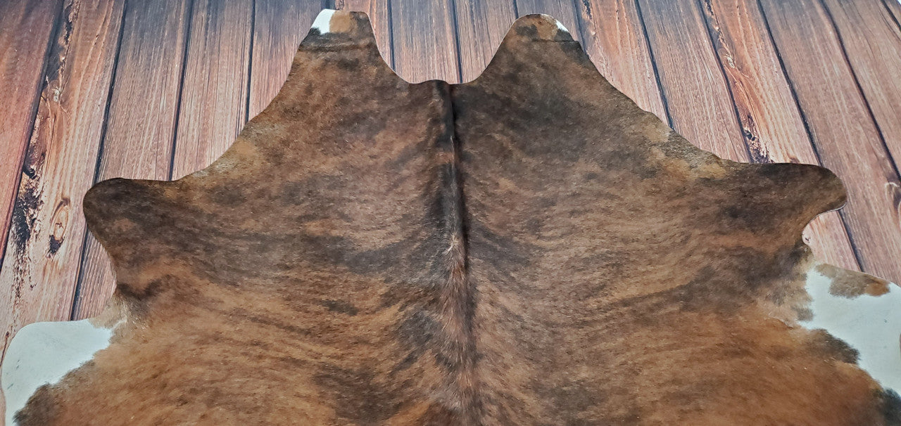 This dark brown cowhide rug will add a rustic, comforting touch to any room. Create the perfect cozy atmosphere with this timeless and classic piece. 