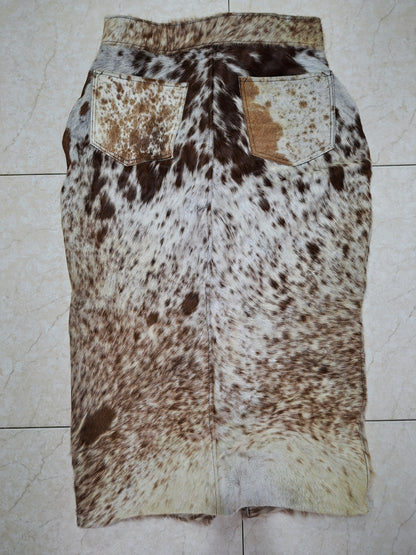 Detail van handgemaakte koeienprint rok met metalen knopen en stevige tailleband.


