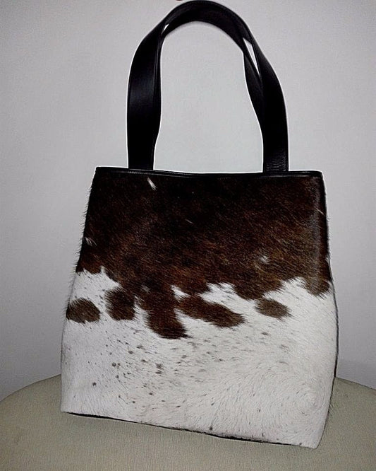 A beautiful cowhide tote bag made from real and natural fur in spotted brown and white, it has soft premium leather handle and two small pockets inside.
