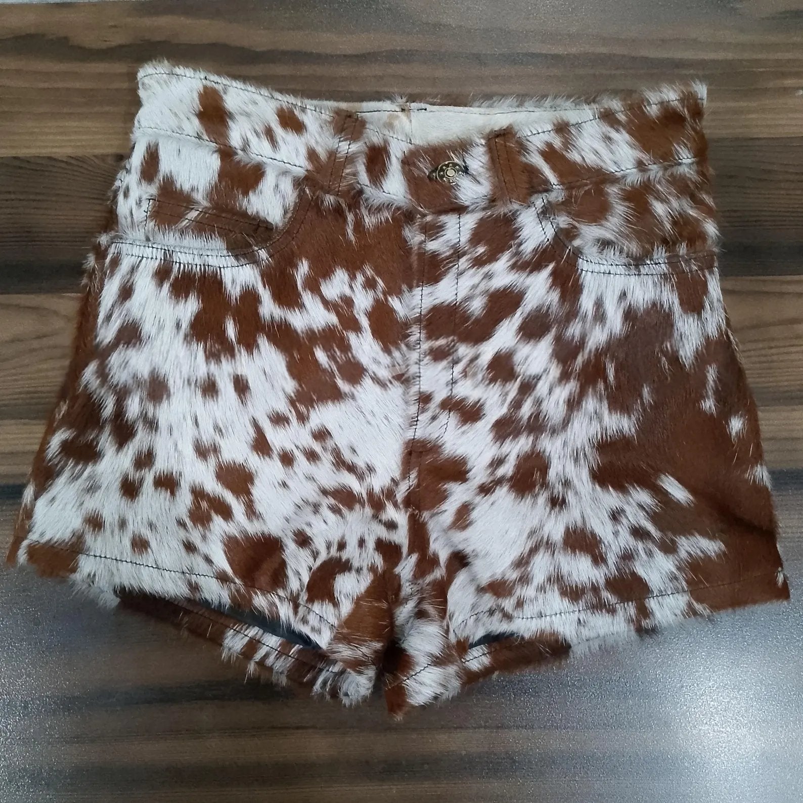Cow print shorts made from genuine brown white cowhide leather. Women's western shorts with natural fur finish and handcrafted edge.
