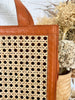 Vierkante rattan handtas met lange schouderriem en rits, perfect als zomeraccessoire.

