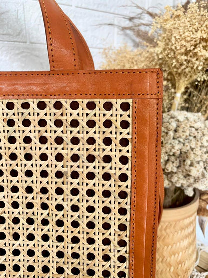Vierkante rattan handtas met lange schouderriem en rits, perfect als zomeraccessoire.

