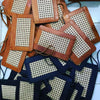 Nahaufnahme der geflochtenen Rattanstruktur und Lederkante der schwarzen Clutch

